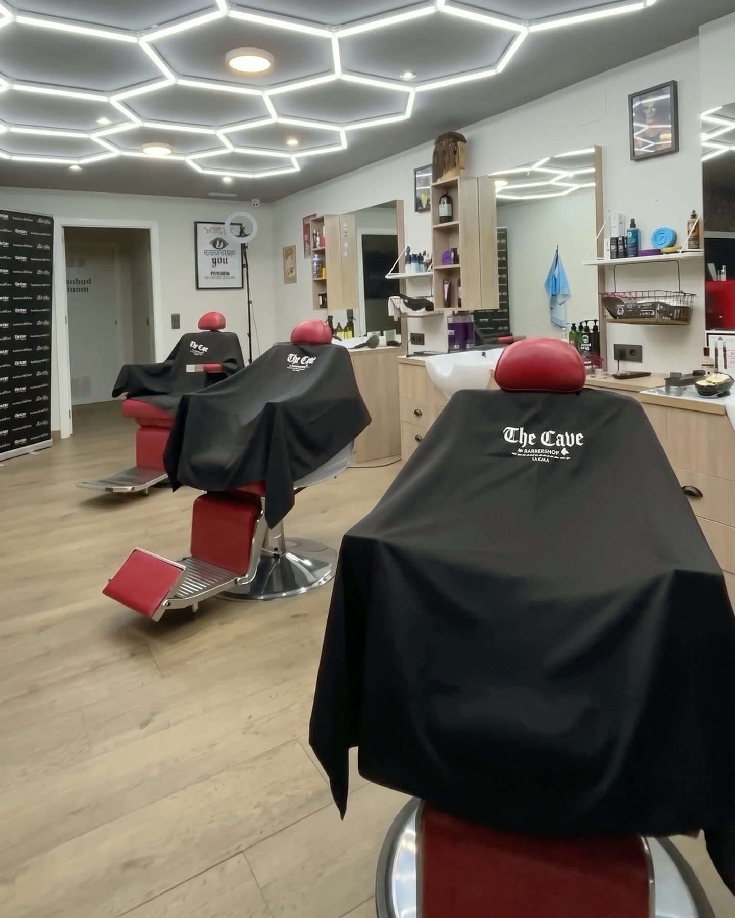 Red barber chairs and branded capes inside The Cave